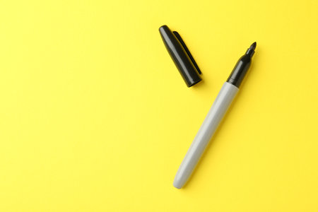 One black marker on yellow background, top view. Space for textの写真素材