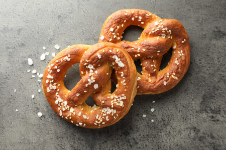 Tasty pretzels with salt on grey table, flat lay