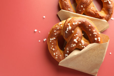 Tasty pretzels with salt on red background, flat lay. Space for textの写真素材