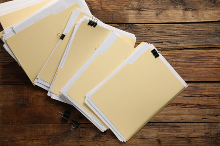 File folders with papers and binder clips on wooden table, flat lay
