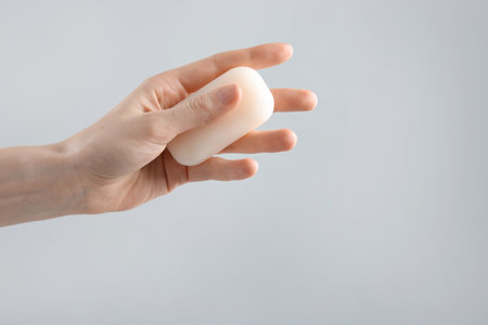 Woman with soap bar on light grey background, closeup. Space for textの写真素材