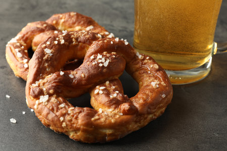 Tasty pretzels and glass of beer on dark textured table, closeupの写真素材