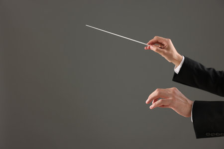 Professional conductor with baton on grey background, closeup. Space for textの写真素材