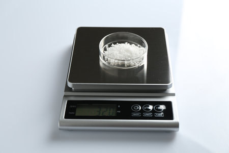 Laboratory scale with Petri dish of sample on white background, closeupの写真素材