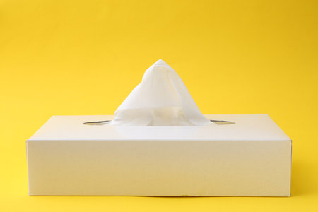 Box with paper handkerchiefs on yellow background. Space for textの写真素材