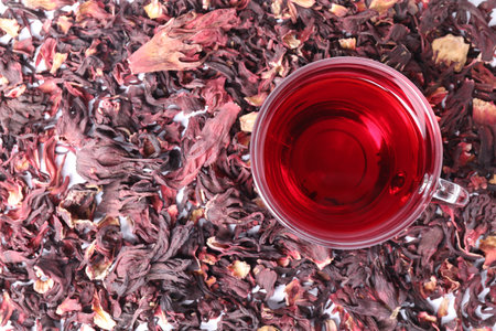 Delicious hibiscus tea in glass cup and dry roselle sepals on table, top viewの写真素材