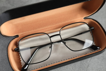 Case with stylish glasses and cleaning cloth on grey table, above viewの写真素材