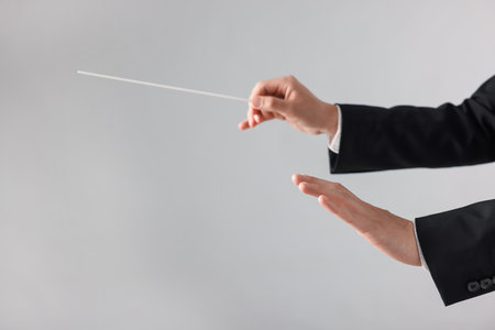 Professional conductor with baton on light grey background, closeup. Space for textの写真素材