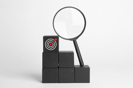 Targeting. Stacked cubes with bullseye and magnifying glass on light backgroundの写真素材