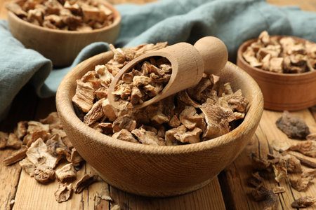 Pieces of dry chicory roots in bowls and scoop on wooden table, closeupの写真素材