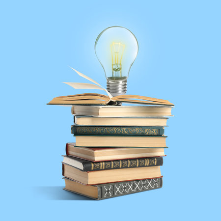 Light bulb on stack of books against light blue background. Idea and knowledgeの写真素材