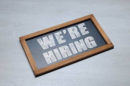 Small blackboard with phrase We Are Hiring on grey wooden background. Recruitment, human resources conceptの写真素材