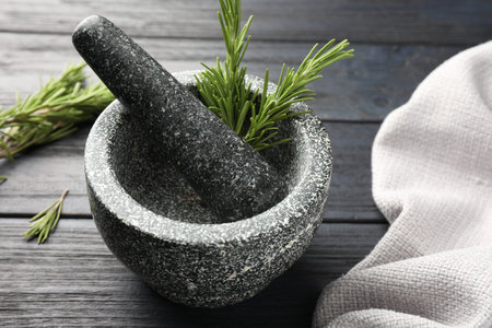 Stone mortar with rosemary and pestle on black wooden table, closeupの写真素材