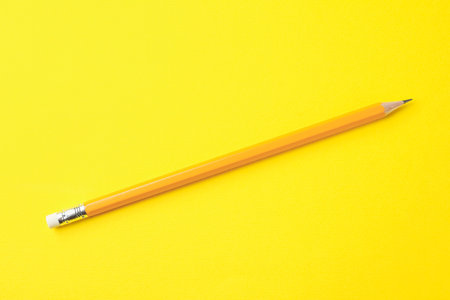 One sharp pencil on yellow background, top view