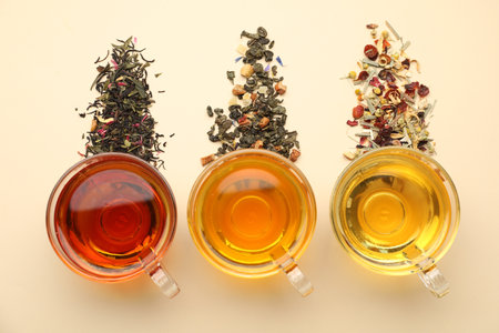 Different freshly brewed teas and dry leaves on beige background, flat layの写真素材