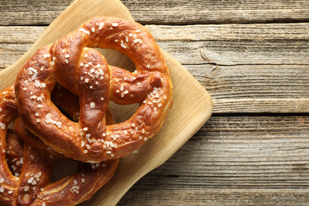 Tasty pretzels with salt on wooden table, top view. Space for text