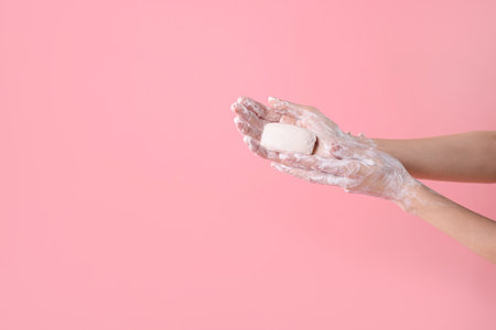 Woman washing hands with soap on light pink background, closeup. Space for textの写真素材