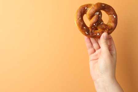 Woman with pretzel on beige background, closeup. Space for textの写真素材