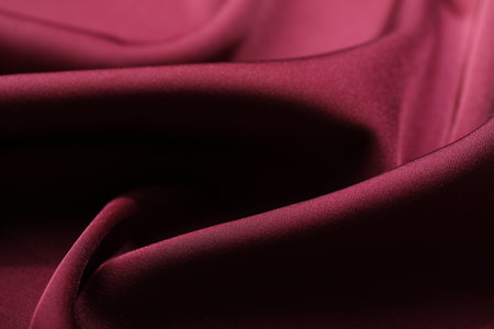 Crumpled burgundy silk fabric as background, closeup