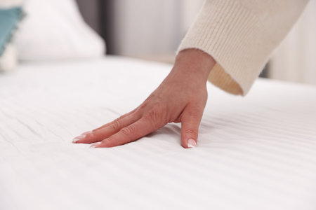Woman touching soft mattress on bed indoors, closeupの写真素材