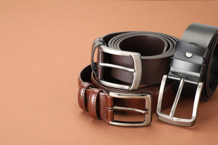 Three leather belts on pale brown background, closeup. Space for textの写真素材