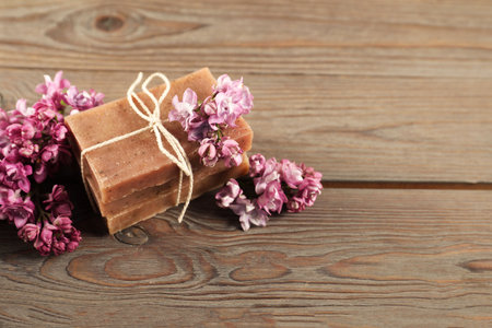 Soap bars and lilac flowers on wooden table, closeup. Space for textの写真素材