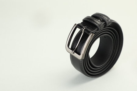 One black leather belt on white background, closeup. Space for text