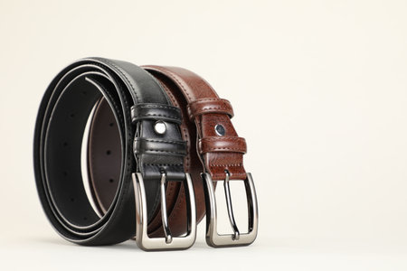 Two leather belts on white background, closeup. Space for text
