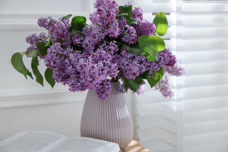 Bouquet of beautiful lilac flowers and book on table indoorsの写真素材