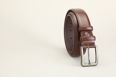 One brown leather belt on white background, closeup. Space for textの写真素材