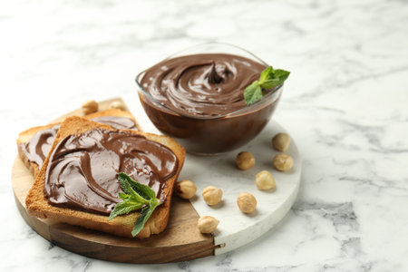 Tasty chocolate spread with mint and hazelnuts on white marble table, closeupの写真素材