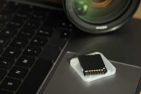 SD memory card, holder and photo camera on laptop, closeup