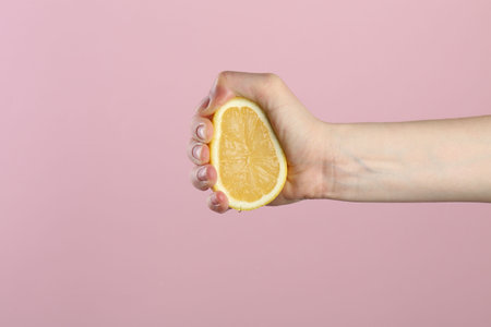 Hand holding lemon on pink background, closeupの写真素材