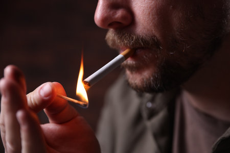 Man lighting cigarette with match on blurred background, closeupのeditorial素材
