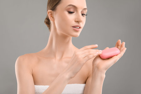 Beautiful woman with soap bar on grey backgroundの写真素材