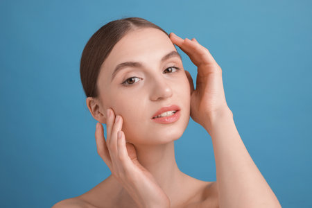 Portrait of charming young woman on light blue backgroundの写真素材