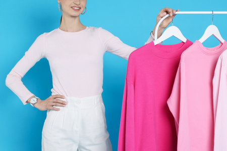 Smiling fashion stylist and rack with clothes on light blue background, closeupの写真素材