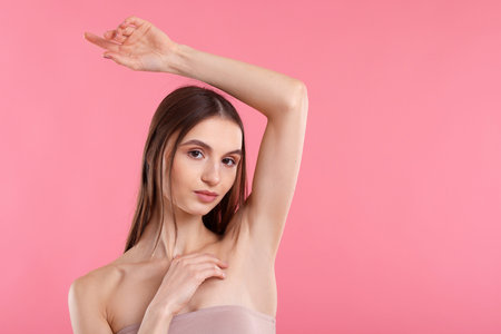 Young woman showing smooth skin after epilation on pink background, space for textの写真素材