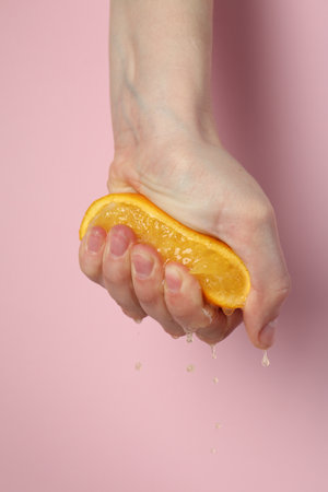 Woman squeezing orange on pink background, closeupの写真素材