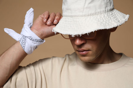 Fashionable portrait of handsome man in stylish outfit on brown backgroundの写真素材