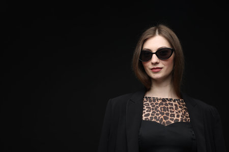 Fashionable portrait of beautiful woman in stylish outfit on black background. Space for textの写真素材