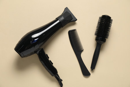 Round brush, comb and dryer on beige background, flat layの写真素材