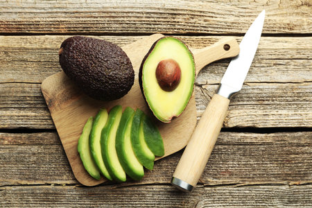 Tasty ripe green avocados and knife on wooden table, flat layの写真素材