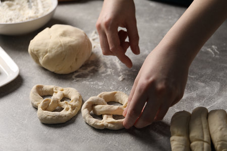 Woman making pretzel at light gray table, closeupの写真素材