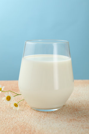 Fresh milk in glass on table against light blue background, closeupの写真素材