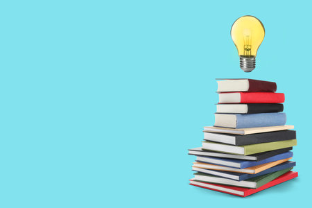 Idea and knowledge. Light bulb in air over stack of books against turquoise background, space for...