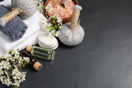 Spa composition with cosmetic products and beautiful flowers on black textured table, above view. Space for textの写真素材