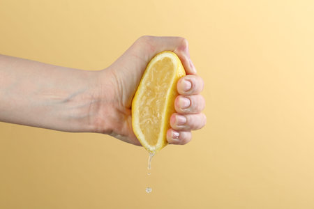 Woman squeezing lemon on yellow background, closeup