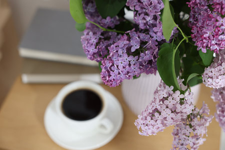 Bouquet of beautiful lilac flowers and coffee on wooden table, closeupの写真素材