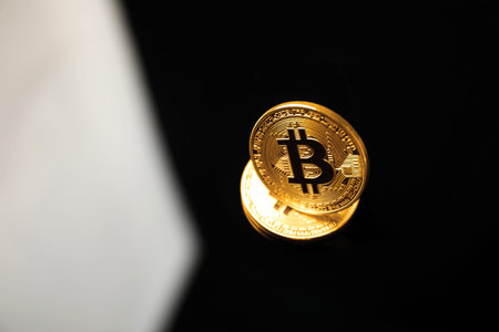 Cryptocurrency. Bitcoins on black mirror surface, above view. Space for text